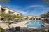 Two Bedroom Apartments in North Gateway AZ - Meritum Sonoran Desert - An exterior shot of the pristine outdoor pool, surrounded by sun loungers and cabanas under a clear blue sky