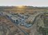 2 Bedroom Apartments in North Gateway AZ - Meritum Sonoran Desert - An aerial view of a modern apartment complex under construction with a stunning desert backdrop at sunset