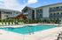Modern apartment complex with inviting swimming pool, elegant poolside loungers, and charming wooden gazebo, perfect for relaxation and community living.