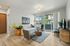 Bright and modern living room with elegant decor, featuring a cozy white sofa, stylish armchairs, large windows, and a sliding door opening to a scenic balcony view.