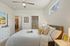 Inviting bedroom with plush bedding, a stylish ceiling fan, and natural light filtering through a window, leading to a modern en-suite bathroom.