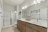 Modern bathroom with sleek double vanity, elegant lighting, and a spacious glass shower.