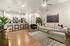 3-Bedroom Apartments in Glendale, AZ - Acero at the Stadium - Open-Concept Living Room With Wood Style Floors, L-Shaped Couch, Armchair, Wall Art, and Modern Ceiling Fan.