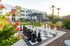Pet-Friendly Apartments in Glendale, AZ - Acero at the Stadium - Outdoor Courtyard With Giant Chess Board, Pergola Seating, Desert Landscaping, and Apartment Buildings In The Background.