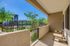 Charming patio view with cozy seating overlooking a lush garden and modern apartment complex under a clear blue sky.