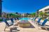 Luxurious apartment complex with a stunning pool, stylish fire pit area, and inviting lounge chairs under clear blue skies.
