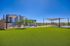 Inviting outdoor area featuring lush green lawn, modern shaded seating areas, and panoramic views under a clear blue sky.