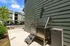 Modern apartment exterior with sleek metal dog washing station, convenient for pet owners. Bright day showcasing clean parking area and well-maintained surroundings.