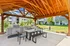 Inviting outdoor gazebo with modern grill stations and dining area, perfect for entertaining in a lush green apartment complex setting.