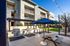 Inviting outdoor communal space featuring modern BBQ grills, stylish string lights, and a shaded picnic area in front of a contemporary apartment building.