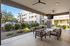 East Mesa, AZ, Pet-Friendly Apartments - Acero Eastmark - Covered Outdoor Lounge With Patio Seating, Ceiling Fans, Mounted Television, and Landscaped Courtyard Views.