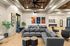 Modern lounge area with contemporary decor, featuring plush gray seating, vibrant artwork, and stylish wood-paneled ceilings.