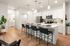 Modern kitchen with sleek white cabinetry, stainless steel appliances, and an inviting island breakfast bar with chic seating, set against warm wooden flooring.