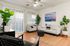 Two-Bedroom Apartments in East Mesa, AZ - Acero Eastmark - Bright Living Room With White Sofa, Accent Chair, Indoor Plants, Wood-Style Flooring, and Glass Doors with Blinds.