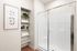 Elegant bathroom with modern glass shower, built-in shelves adorned with lush greenery and towels, and tasteful botanical wall art.