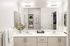 Elegant bathroom with double sinks, modern fixtures, and ambient lighting, featuring minimalist decor and a touch of greenery.