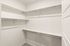 Spacious walk-in closet with ample shelving and hanging space, ideal for organized storage solutions.