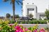 Charming Acero Val Vista Apartment Homes entrance with lush greenery and vibrant flowers in a serene neighborhood.