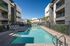 Modern apartment complex featuring a sparkling swimming pool, surrounded by sleek lounge chairs and shaded canopies, providing a luxurious and relaxing outdoor escape.