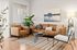 Inviting living room with a modern brown sofa set, stylish coffee table, and lush green plants, bathed in soft natural light.