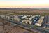 Aerial view of a modern apartment complex surrounded by serene desert landscape, featuring multiple buildings and a central pool area.