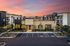 Stunning sunset view of a modern apartment complex with lush landscaping and inviting entryway.