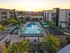 Chic apartment complex featuring a stunning central pool surrounded by lush greenery and modern architecture, perfect for relaxation and leisure.