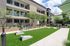 Modern apartment exterior with spacious courtyard, lush greenery, and inviting lounge seating.
