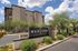 Modern apartment complex with lush desert landscaping and bold signage under a bright blue sky.