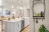 Modern open-plan kitchen with elegant white countertops, stylish pendant lighting, and chic bar seating leading into a cozy living room.