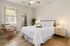 Bright and inviting bedroom featuring a plush bed with crisp white linens, modern furniture, and a spacious walk-in closet.