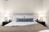 Elegant bedroom featuring a plush bed with decorative pillows, modern bedside lamps, and cozy accents.