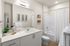 Modern bathroom showcasing sleek white cabinetry, elegant countertop, and stylish decor with a refreshing shower and greenery accents.