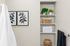 Elegant bathroom nook with modern plant decor, framed botanical art, and plush towels neatly arranged on shelves.