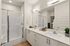 Modern bathroom with sleek double sink vanity, chic glass shower enclosure, and stylish decor, perfect for a contemporary apartment.
