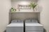 Modern laundry room with stylish washer and dryer, accented by shelf decor featuring vibrant plants and a decorative sign.
