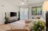 Inviting living room with modern decor, featuring a cozy sectional sofa, sleek TV setup, and lush indoor plants, illuminated by natural light.