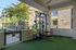 Modern outdoor gym featuring a well-equipped squat rack and plates, overlooking a serene garden view.
