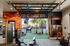 Modern fitness center with open garage-door concept, vibrant cactus mural, and state-of-the-art gym equipment, offering a scenic view of the outdoor area.