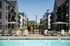 Elegant apartment complex with modern balconies, lush landscaping, and inviting poolside view, perfect for relaxation.