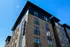 Modern apartment building with sleek brick facade and expansive windows at 25th & Quincy under a clear blue sky.