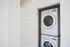 Modern apartment laundry room with sleek, space-saving stacked washer and dryer behind a chic white door.