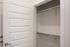 Spacious walk-in closet with modern shelving and a sleek white door, perfect for organized living.