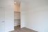 Bright minimalistic room with an open walk-in closet, featuring sleek wooden flooring and modern lighting.