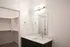Modern bathroom featuring sleek vanity with integrated sink, spacious mirror, and a walk-in closet.