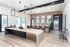 Modern kitchen with sleek wood floors, large island, and contemporary lighting featuring a brick accent wall and stainless steel appliances.
