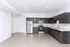 Modern kitchen with sleek dark cabinets, stainless steel appliances, and bright lighting in a spacious open-plan apartment.