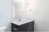 Elegant bathroom with sleek modern vanity, glossy white countertop, and large mirror creating a bright, spacious ambiance.