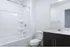 Sleek and modern bathroom featuring a pristine white bathtub and elegant dark wood vanity with chrome fixtures.