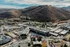 Scenic aerial view of a modern apartment complex nestled in a picturesque valley surrounded by rolling hills, showcasing harmonious urban living amidst nature.